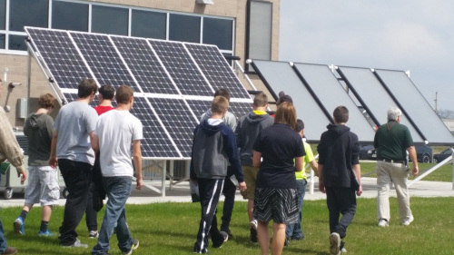 A high school class walking in front of a solar array